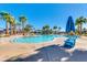 Large community pool surrounded by palm trees, blue umbrellas, and lounge chairs at 2120 N Heritage St, Buckeye, AZ 85396