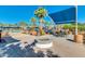 Community pool area featuring a modern pergola, outdoor seating, fireplace, and lush landscaping on a sunny day at 2120 N Heritage St, Buckeye, AZ 85396