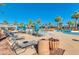 Community pool with lounge chairs and tables surrounded by palm trees and landscaping on a sunny day at 2120 N Heritage St, Buckeye, AZ 85396