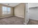 An airy bedroom with neutral walls and carpet, a closet, and a large window for natural light at 240 W Juniper Ave # 1211, Gilbert, AZ 85233