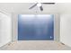 This carpeted bedroom has a blue accent wall, ceiling fan and built-in shelving at 2529 N Barber Dr, Mesa, AZ 85215