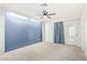 Spacious carpeted bedroom with a ceiling fan, blue accent wall and a door to the outside at 2529 N Barber Dr, Mesa, AZ 85215