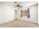 This carpeted bedroom features a ceiling fan, closet and a large window at 2529 N Barber Dr, Mesa, AZ 85215