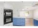 This kitchen features white and blue cabinets, modern appliances, and wood flooring at 2529 N Barber Dr, Mesa, AZ 85215