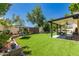 Green backyard with artificial turf, covered patio, swing, and mature landscaping at 4627 W Laurie Ln, Glendale, AZ 85302