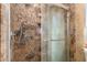 Elegant walk-in shower with decorative marble-style tile, glass door, and recessed storage at 4627 W Laurie Ln, Glendale, AZ 85302