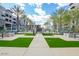 A welcoming courtyard features lush artificial turf, modern outdoor furniture, and fire pits with palm trees on a sunny day at 5250 E Deer Valley Dr # 146, Phoenix, AZ 85054