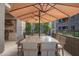 Elegant outdoor dining area with a marble-top table, seating for eight, and a large umbrella for shade on a patio at 5250 E Deer Valley Dr # 146, Phoenix, AZ 85054