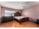 Spacious bedroom with wood floors and a large bed, illuminated by a ceiling fan and window at 5432 W Sunnyside Dr, Glendale, AZ 85304