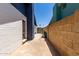 Narrow side yard featuring a concrete path between the house and a brick wall with a locked gate at 5432 W Sunnyside Dr, Glendale, AZ 85304