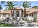 Elegant home with a well-manicured lawn, mature palm trees, and a stunning arched entrance at 10300 N 48Th Pl, Paradise Valley, AZ 85253