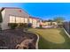 Spacious backyard with a lush lawn, putting green, mature trees, and a covered patio overlooking the beautiful pool at 12809 W Oyer Ln, Peoria, AZ 85383