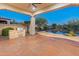 Outdoor kitchen with view of the pool featuring a rock waterfall and lush desert landscaping, creating a backyard oasis at 12809 W Oyer Ln, Peoria, AZ 85383