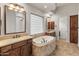 Bathroom with a soaking tub, double vanities, tile flooring and travertine tub surround at 12809 W Oyer Ln, Peoria, AZ 85383