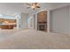 Open-concept living room featuring a stone fireplace, plush carpeting, and seamless flow into the gourmet kitchen at 12809 W Oyer Ln, Peoria, AZ 85383