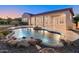 Backyard oasis featuring a free form pool with rock accents, a covered patio, and lush landscaping at 12809 W Oyer Ln, Peoria, AZ 85383