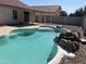 Refreshing pool with rock waterfall feature, tanning ledge and fence creating an inviting backyard retreat at 15731 W Evans Dr, Surprise, AZ 85379