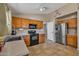 Traditional-style kitchen with tile floors, light wood cabinets, stainless steel refrigerator, and black appliances at 15737 W Lundberg St, Surprise, AZ 85374
