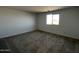 Bright carpeted bedroom with white walls and large window offering a view of the neighborhood at 17535 W Fulton St, Goodyear, AZ 85338