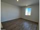 Bright bedroom with wood-look tile flooring, white walls, and a window letting in natural light at 17535 W Fulton St, Goodyear, AZ 85338