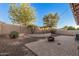 Landscaped backyard featuring mature trees, brick-paved patio area, and a fire pit, ideal for outdoor relaxation and entertainment at 1783 W Cool Water Way, San Tan Valley, AZ 85144
