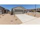 Single-story house with two-car garage, desert landscaping, and a view of the neighborhood on a sunny day at 18340 W Patrick Ln, Surprise, AZ 85387