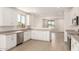 Modern kitchen with white cabinets, stainless steel appliances, gray countertops, and wood-look tile flooring at 18340 W Patrick Ln, Surprise, AZ 85387