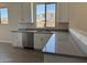 Close-up of the kitchen featuring stainless steel dishwasher, sink, and modern gray countertops at 18340 W Patrick Ln, Surprise, AZ 85387