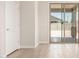 Bright living room with neutral walls, a door, and wood-look tile flooring leading to a patio at 18340 W Patrick Ln, Surprise, AZ 85387