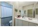 Well-lit bathroom featuring a white vanity, large mirror, and a shower with a striped curtain at 19969 N Santa Cruz Dr, Maricopa, AZ 85138