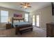 Large primary bedroom with a wooden bed frame, ceiling fan, and sliding glass doors at 19969 N Santa Cruz Dr, Maricopa, AZ 85138