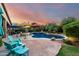 Resort-style backyard oasis featuring a sparkling pool, spa, lush landscaping, and lounge areas under colorful umbrellas at 2058 E Marlene Dr, Gilbert, AZ 85296