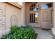 Arched entry with decorative security door surrounded by a flowering garden bed and an outdoor light fixture at 2058 E Marlene Dr, Gilbert, AZ 85296