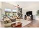 Inviting living room featuring a cozy fireplace, plush sofas, large windows, ceiling fan, and dark wood floors at 2058 E Marlene Dr, Gilbert, AZ 85296