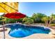 Inviting backyard pool with a red umbrella and lush greenery, creating a serene oasis at 2058 E Marlene Dr, Gilbert, AZ 85296