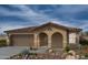 Inviting single-story home featuring a charming covered entry and a two-car garage, set against a beautiful cloudy sky at 21114 E Arrowhead Trl, Queen Creek, AZ 85142