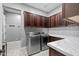 A laundry room features stainless steel washer and dryer, lots of dark wood cabinet space, and counter top space at 3049 E Longhorn Dr, Gilbert, AZ 85297