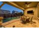 Relaxing covered patio with ceiling fan, outdoor dining area, and a view of the sparkling pool with a waterfall at 3049 E Longhorn Dr, Gilbert, AZ 85297
