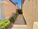Side view of a walkway leading to a private gate, enhanced by verdant landscaping and desert flora at 3440 E Southern Ave # 1088, Mesa, AZ 85204