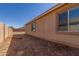 Side view of a tan home showcasing a dirt backyard with a block fence at 40027 W Pryor Ln, Maricopa, AZ 85138