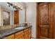 A well-lit bathroom featuring a dark granite countertop, a wood door, and neutral-toned walls at 6305 E Arabian Way, Paradise Valley, AZ 85253