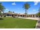 Expansive home exterior featuring lush green lawn, mature palm trees and a circular driveway at 6305 E Arabian Way, Paradise Valley, AZ 85253