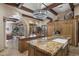 Open kitchen with granite counters, wooden beams, a crystal chandelier, and an island with a sink at 6305 E Arabian Way, Paradise Valley, AZ 85253