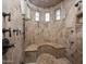 Luxurious travertine shower with a built-in bench and windows, offering a spa-like experience at home at 6305 E Arabian Way, Paradise Valley, AZ 85253