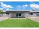 Spacious backyard featuring artificial grass, gravel landscaping, and a covered patio with sliding glass doors at 6420 S Wilson St, Tempe, AZ 85283