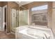 Bright bathroom with a soaking tub, glass-enclosed shower, and a window overlooking the backyard at 6758 W Quail Ave, Glendale, AZ 85308