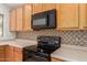 Kitchen features a flat top range and microwave with beautiful wood cabinets and trim at 6758 W Quail Ave, Glendale, AZ 85308