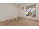 Bright living room with plush carpet, white walls, and a view of the front yard through large windows at 6758 W Quail Ave, Glendale, AZ 85308