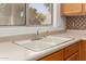 Close-up of a stainless steel sink and countertop, capturing natural light from nearby window at 6758 W Quail Ave, Glendale, AZ 85308
