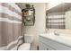 Cozy bathroom with storage shelves, white fixtures, and a shower curtain at 7603 W Oraibi Dr, Glendale, AZ 85308